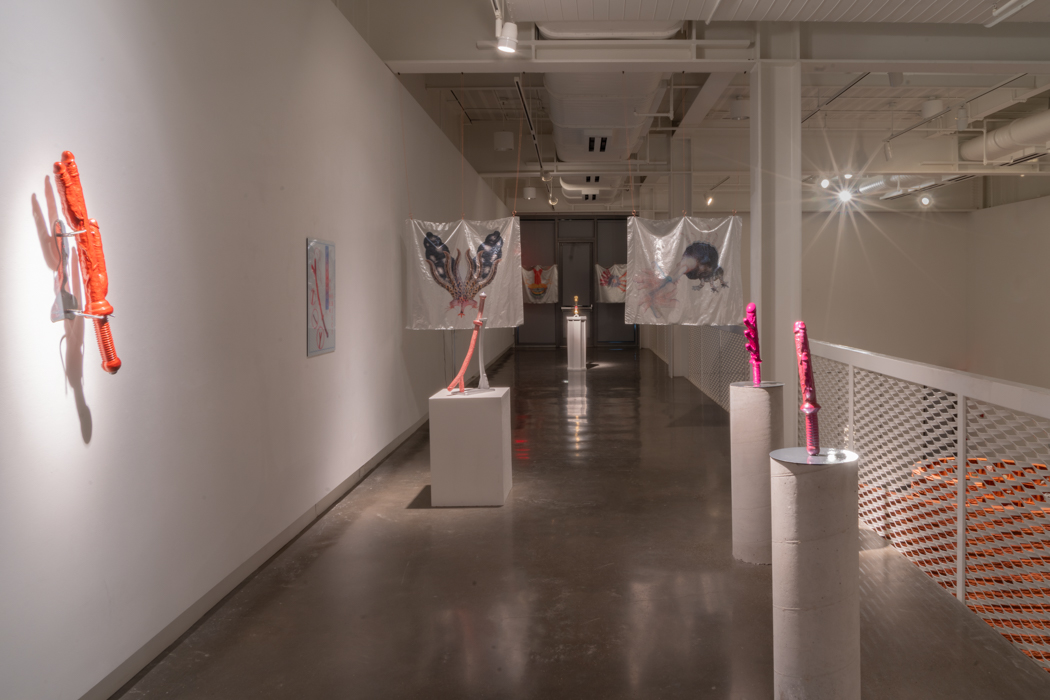  A hallway with various illuminated artworks, including wall sculptures and hanging fabric pieces.