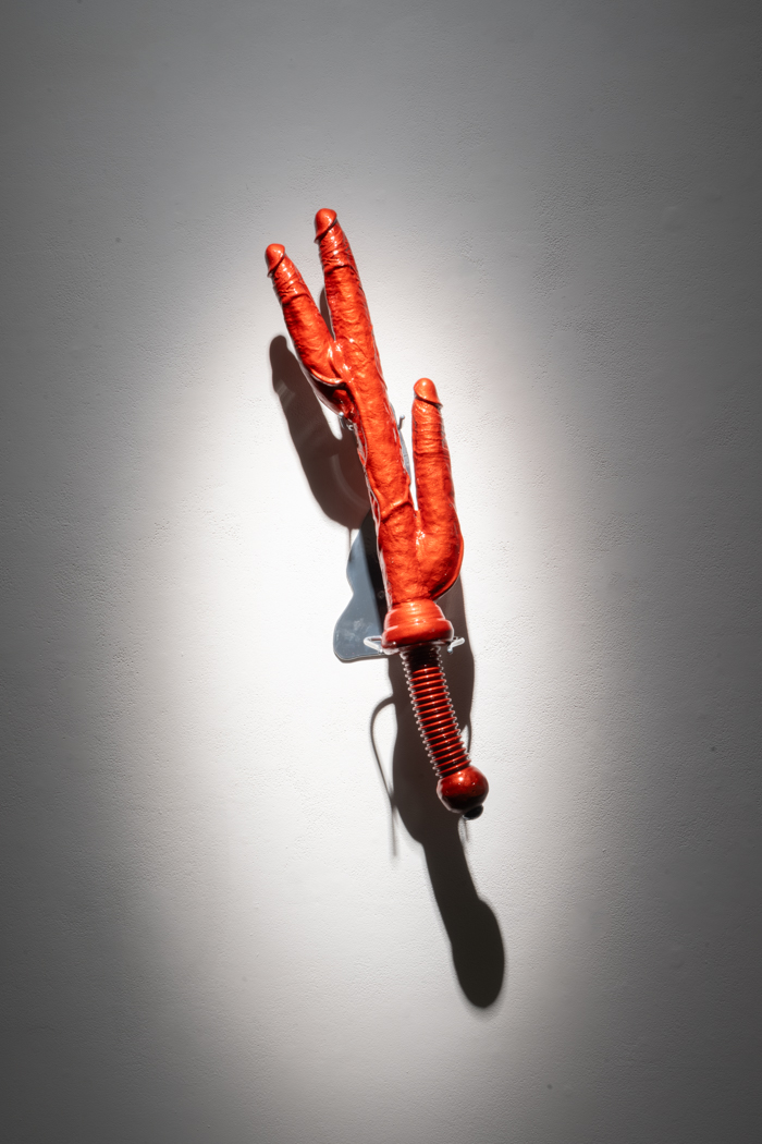 A red sculptural piece on the wall resembling a claw or hand gripping a handle.