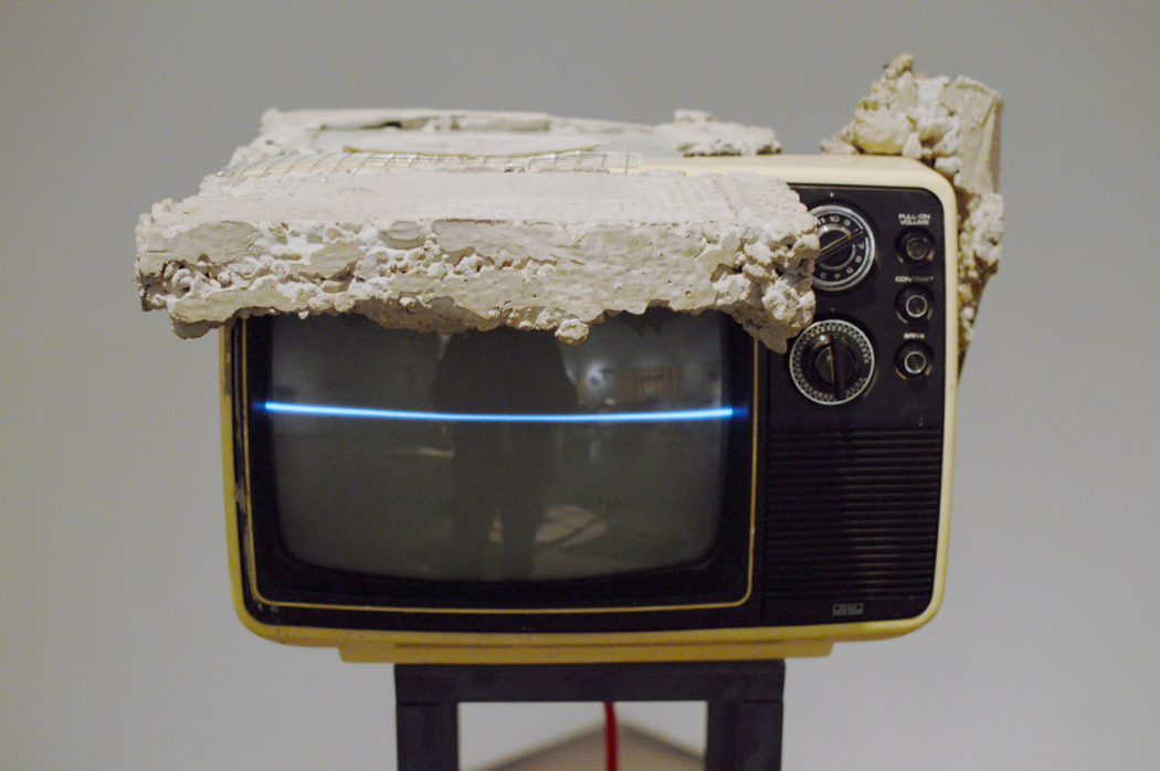 Old television encased in concrete as part of an art installation.