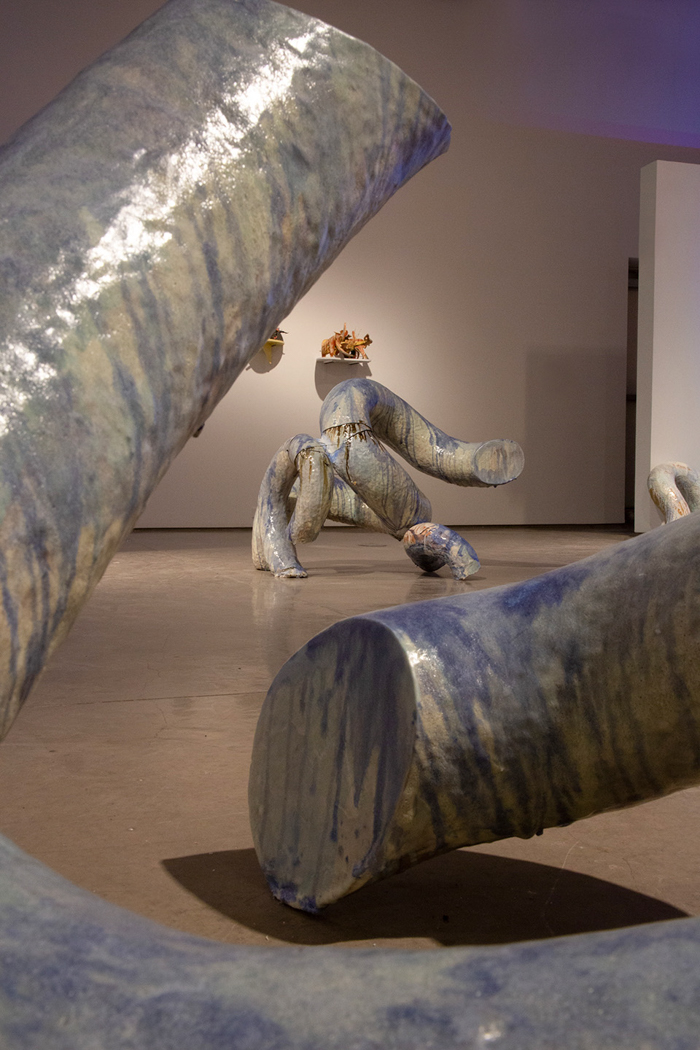 Gallery room with curved ceramic sculptures and wall-mounted pieces.