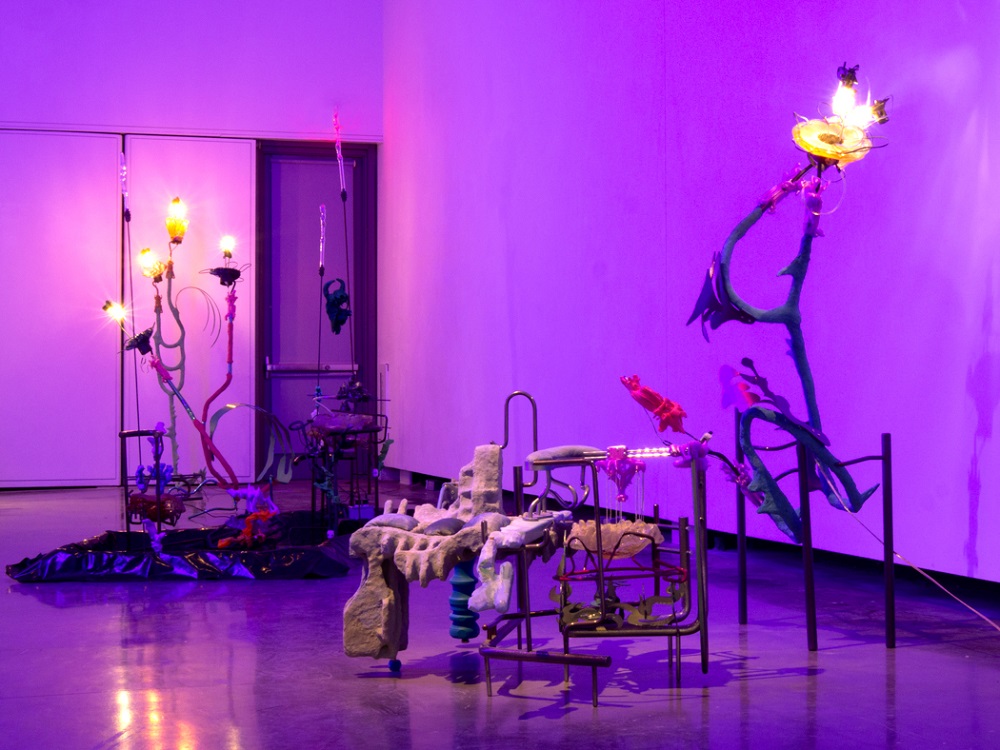 Abstract sculptures illuminated by colorful lights in a surreal installation.