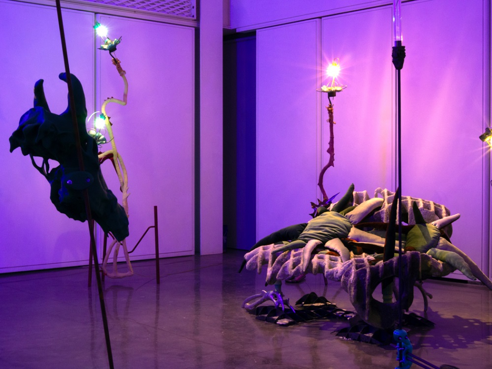 Dimly lit gallery with abstract sculptures and glowing fixtures