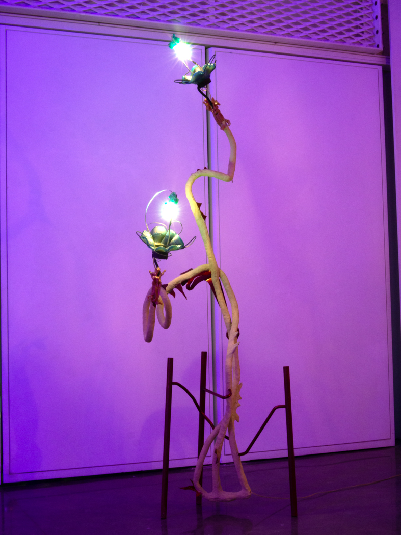 Tall sculpture with glowing flower-like elements against a purple backdrop.