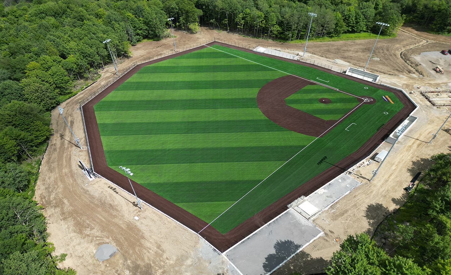 Three people standing in front of the AU Saxons Sports Complex sign at a construction site
