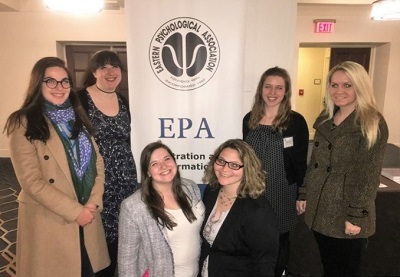 A group of psychology students pose beside an Eastern Psychological Association banner at a professional conference.