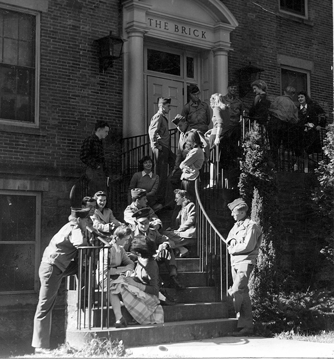 A black and white photo of people sitting on the steps of a building