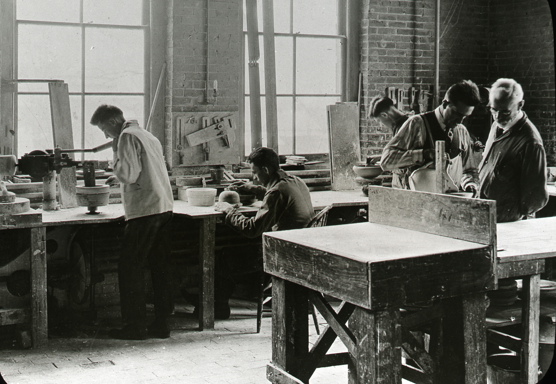 A black and white photo of a professor teaching ceramics in a lab